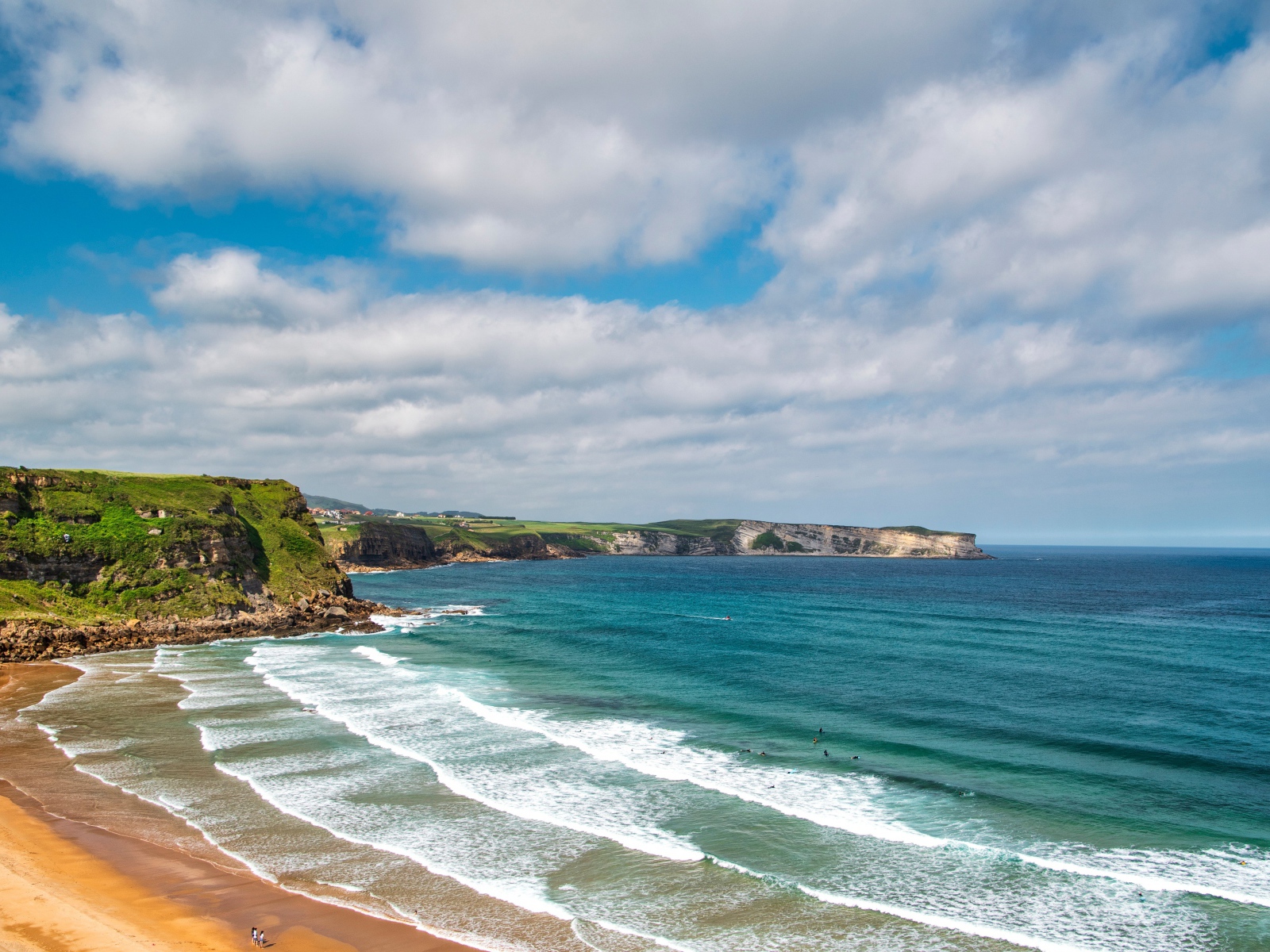 Спокойные волны на берегу залива под голубым небом с облаками