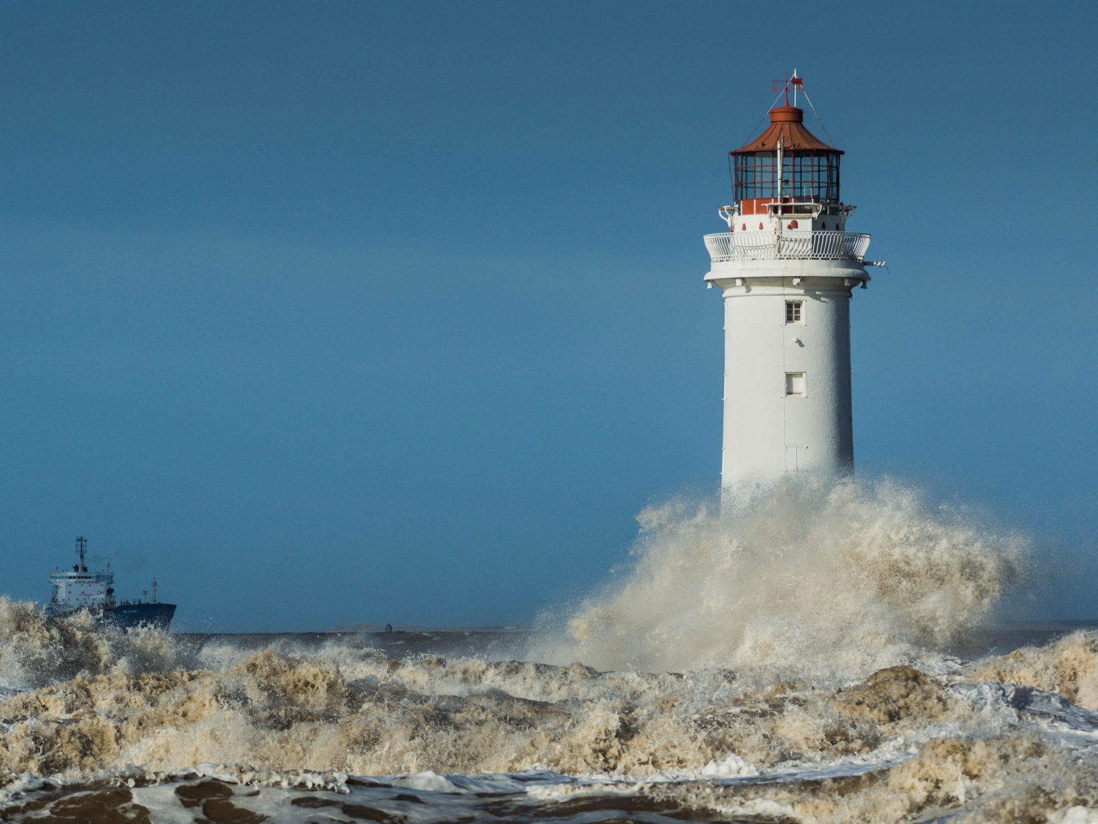 Бушующие белые волны бьются о маяк 