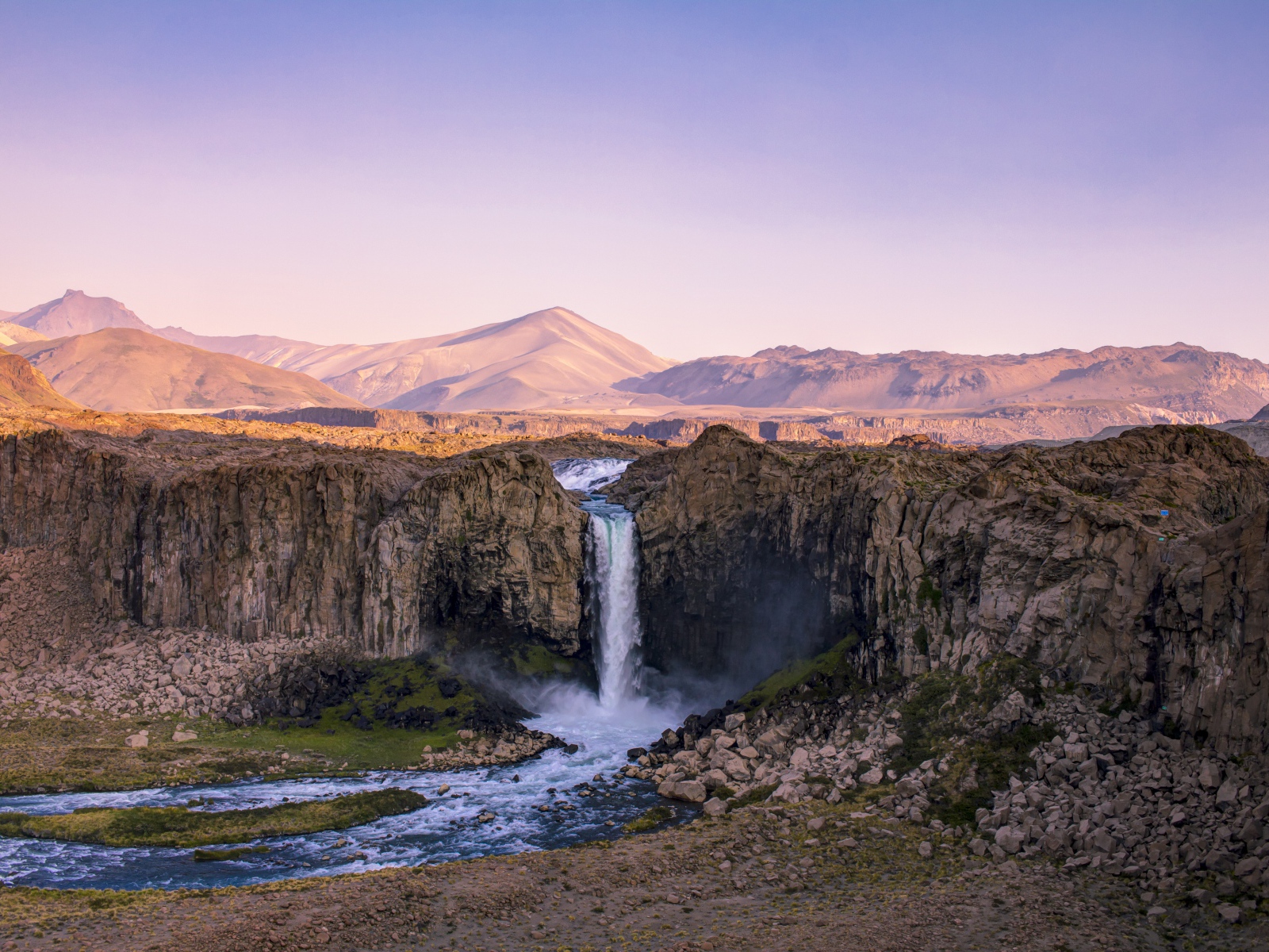 Водопад стекает по каменному склону горы на рассвете 