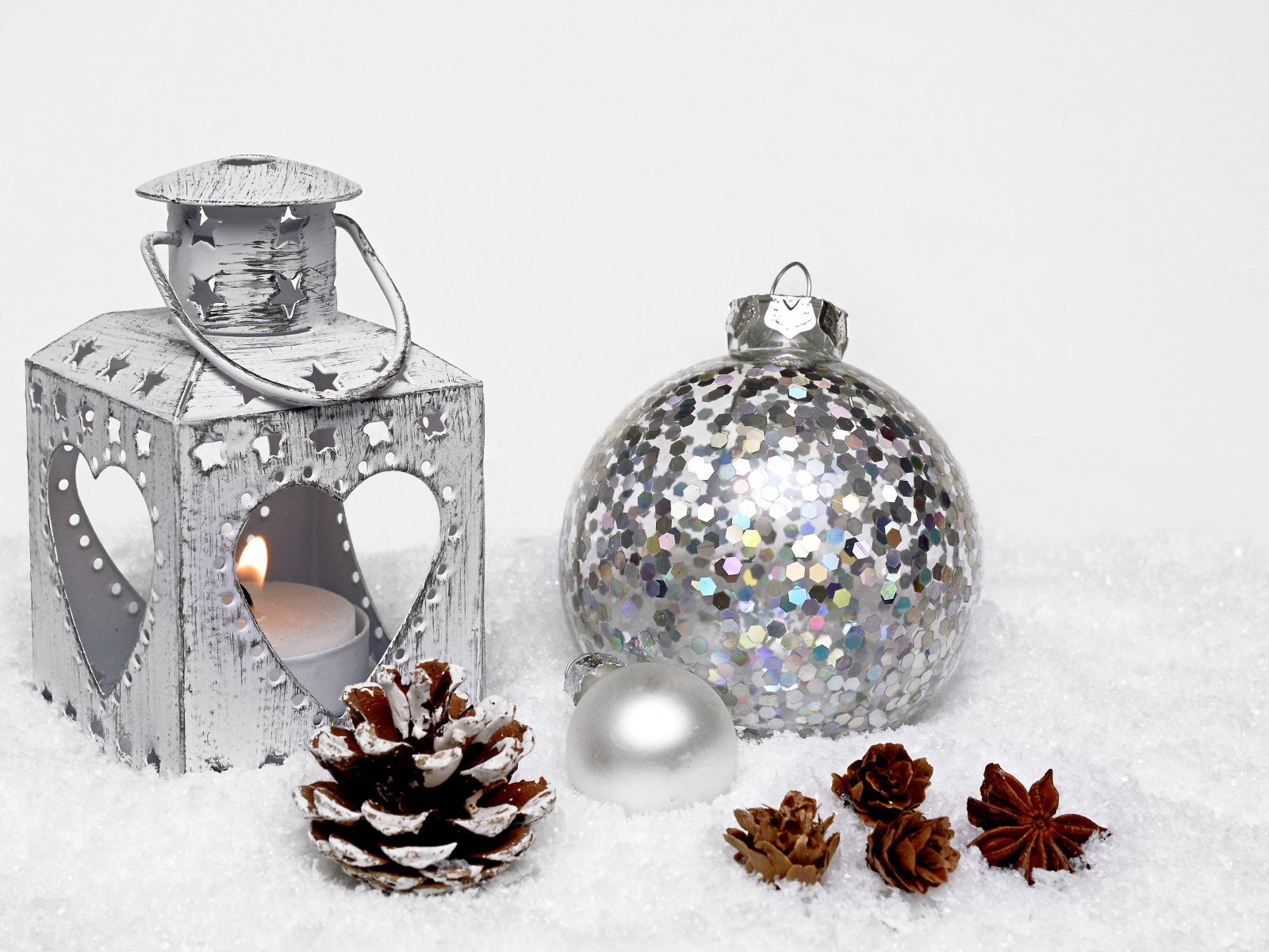 Фонарик и елочный шар с шишками на снегу