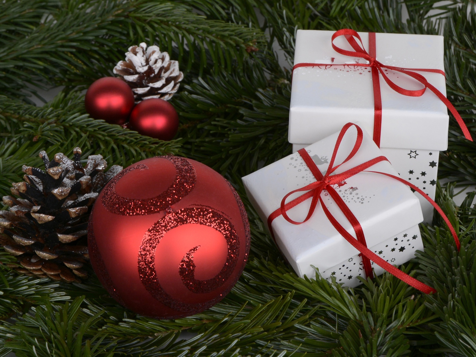Два белых подарка, красный шар и еловая ветка на новый год 