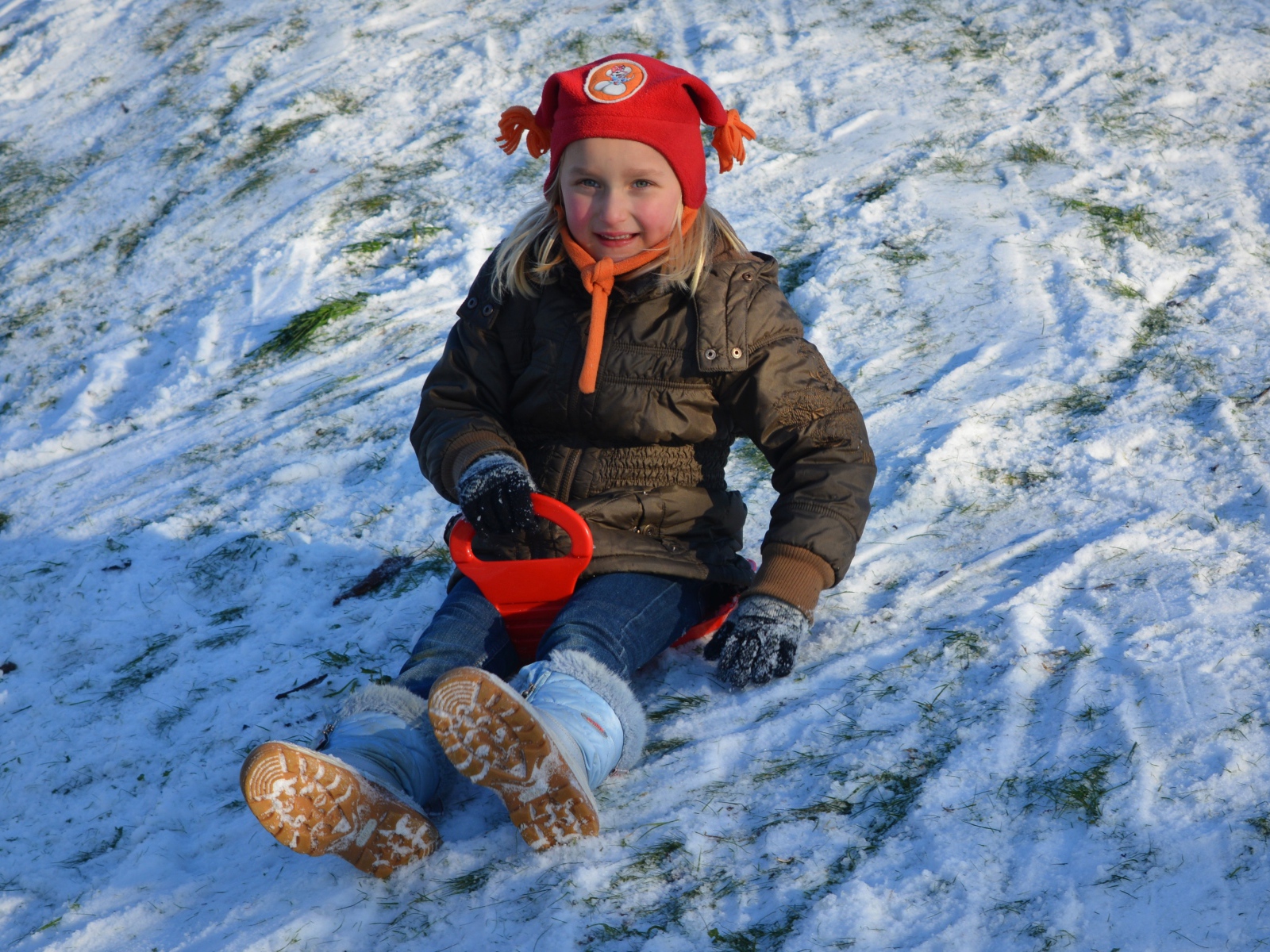 Маленькая девочка катится с горки по снегу