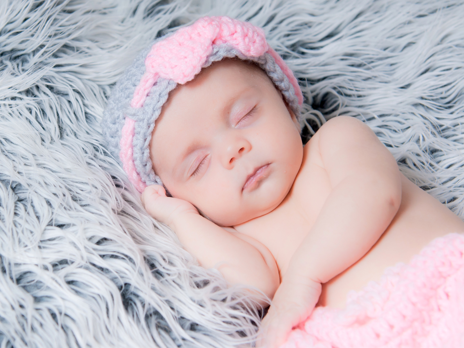 Грудной ребенок спит на меховом одеяле 