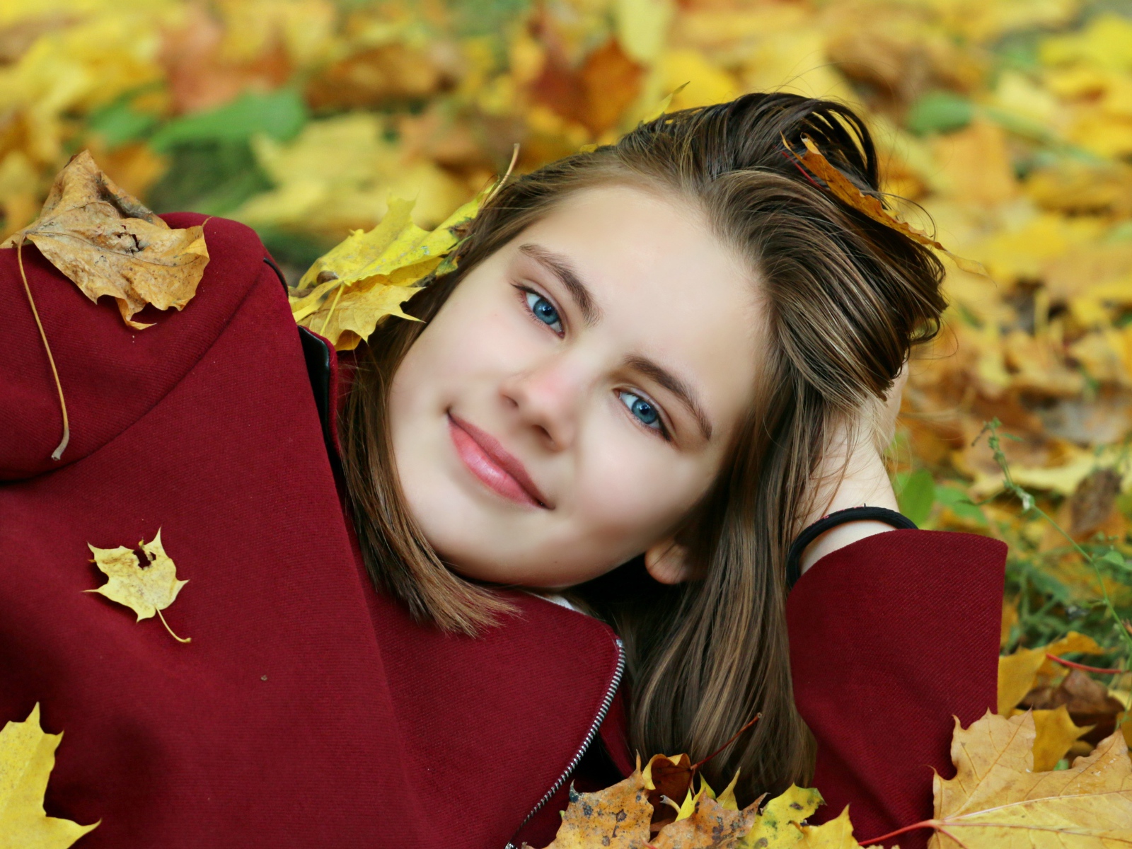 Красивая голубоглазая девочка лежит на опавшей листве