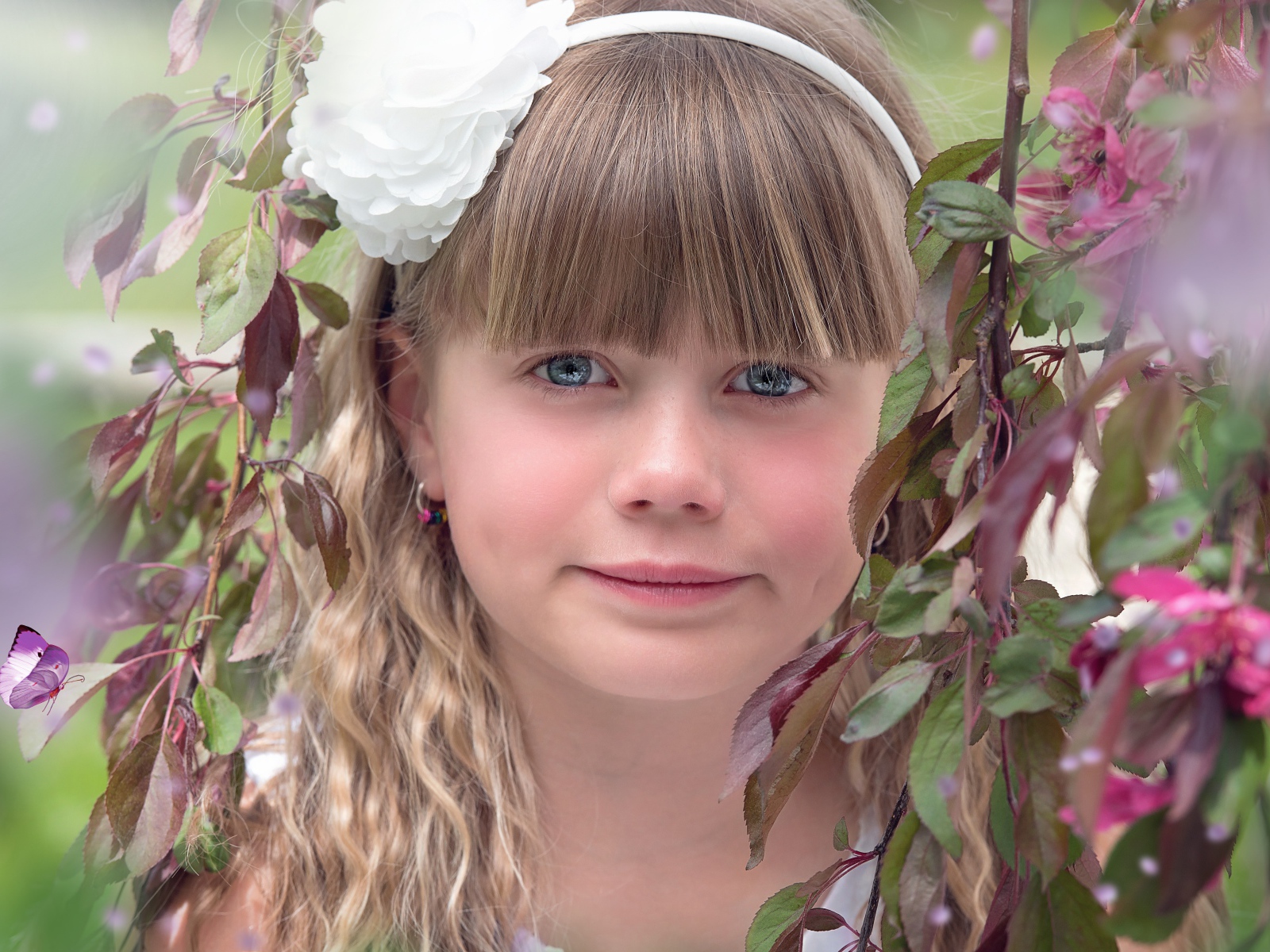Красивая голубоглазая девочка с белым цветком на голове 