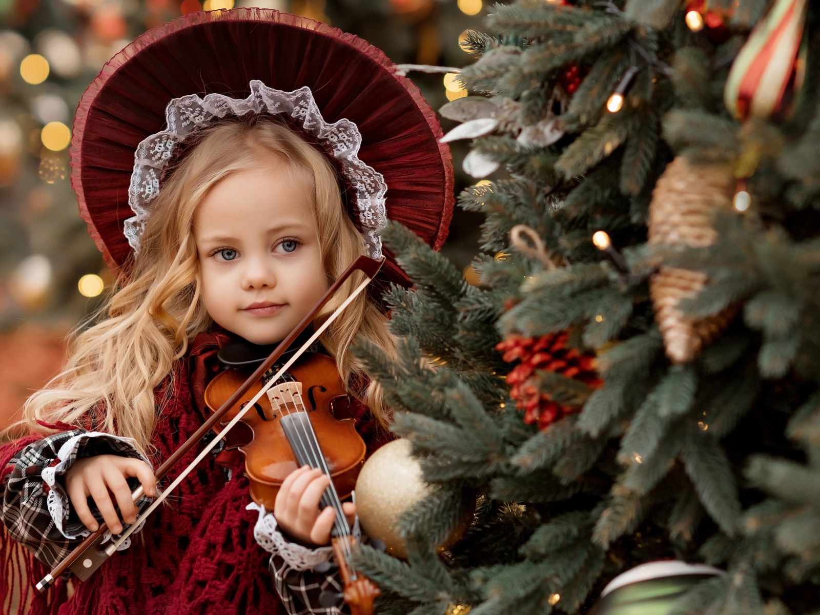 Красивая маленькая девочка со скрипкой у ели