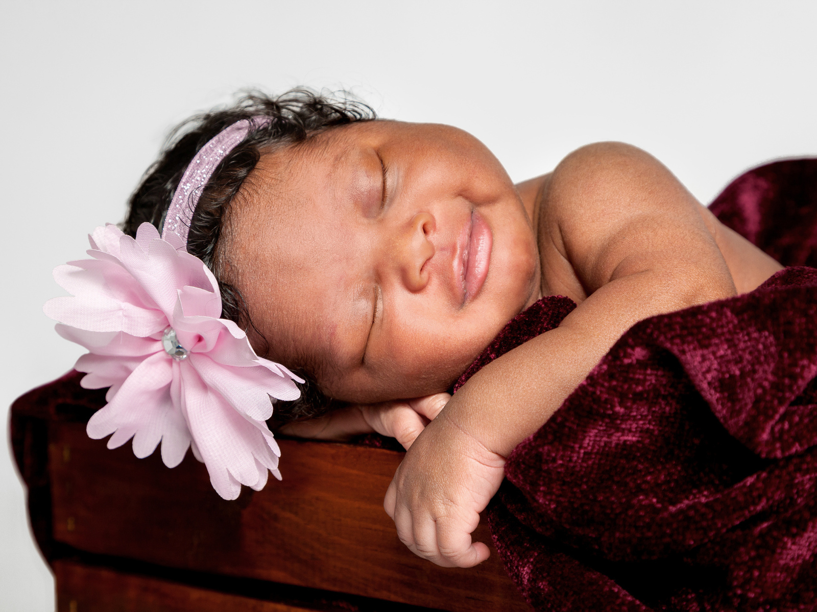 Темнокожая маленькая девочка с розовым цветком на голове 