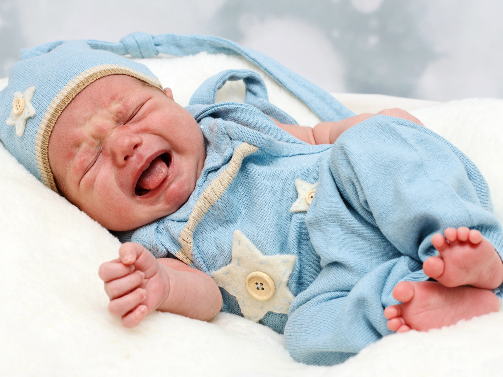 Плачущий грудной ребенок в голубом костюме