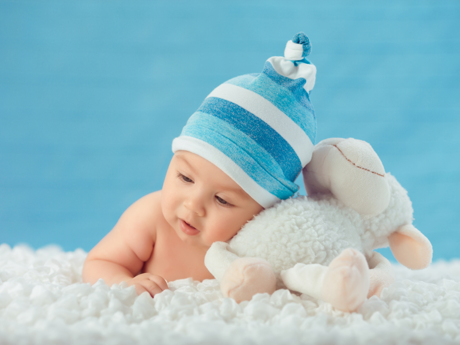 Забавный малыш с игрушкой на голубом фоне