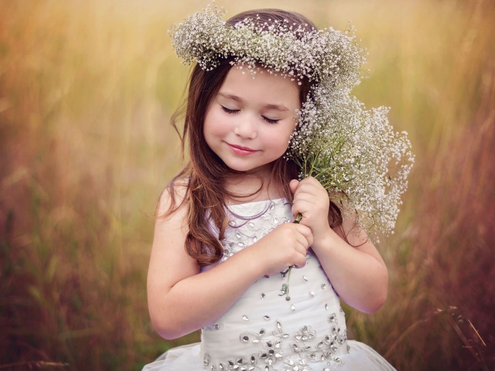 Маленькая девочка в венке с букетом полевых цветов