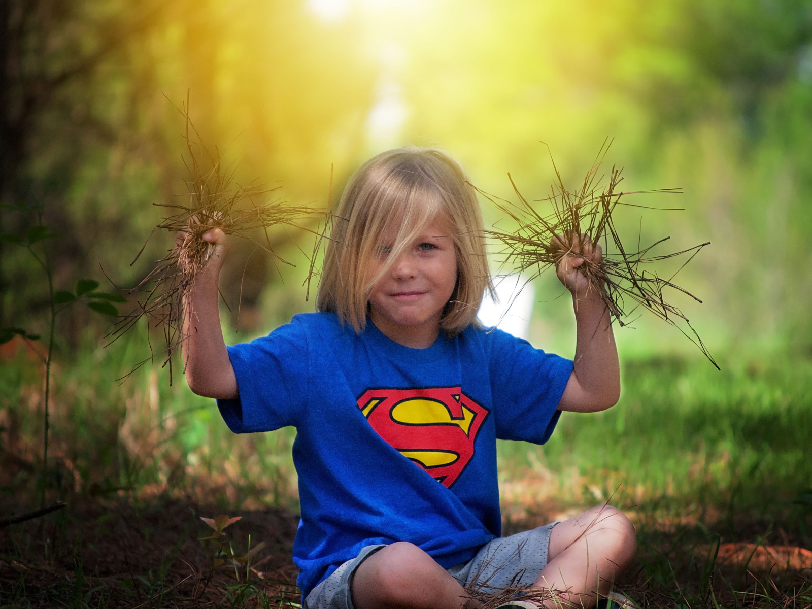Маленькая девочка сидит на земле с травой