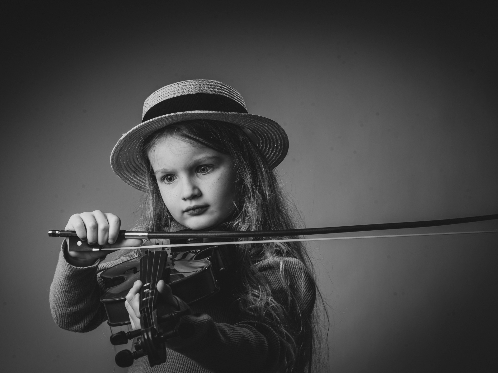 Маленькая девочка со скрипкой в руках на сером фоне