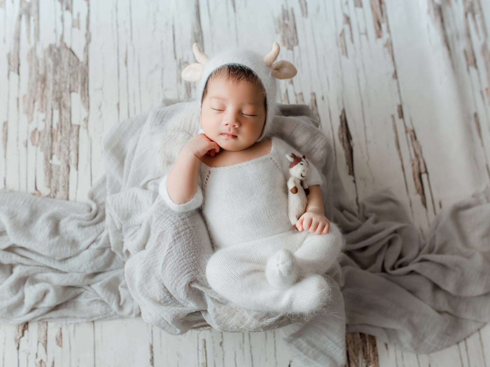 Маленький спящий грудной ребенок в белом костюме