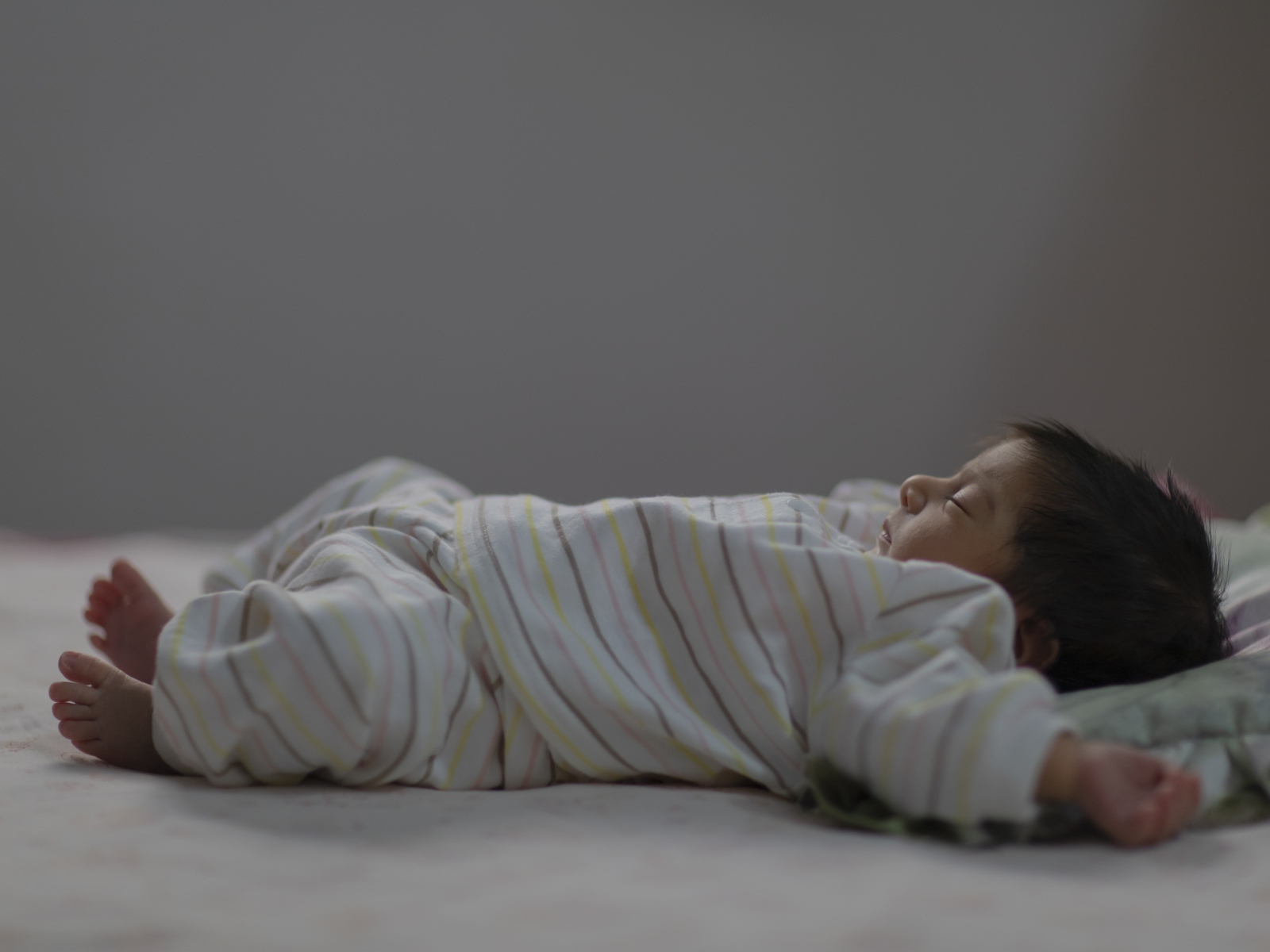 Маленький спящий грудной ребенок на кровати 