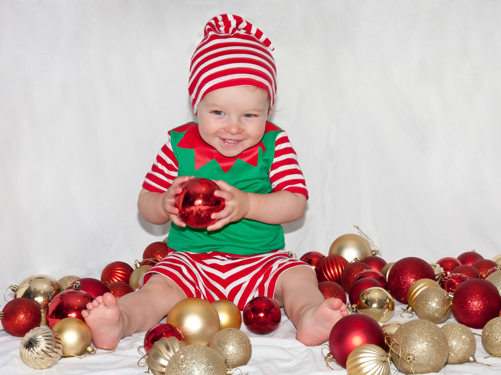 Маленький улыбающийся мальчик с елочными украшениями