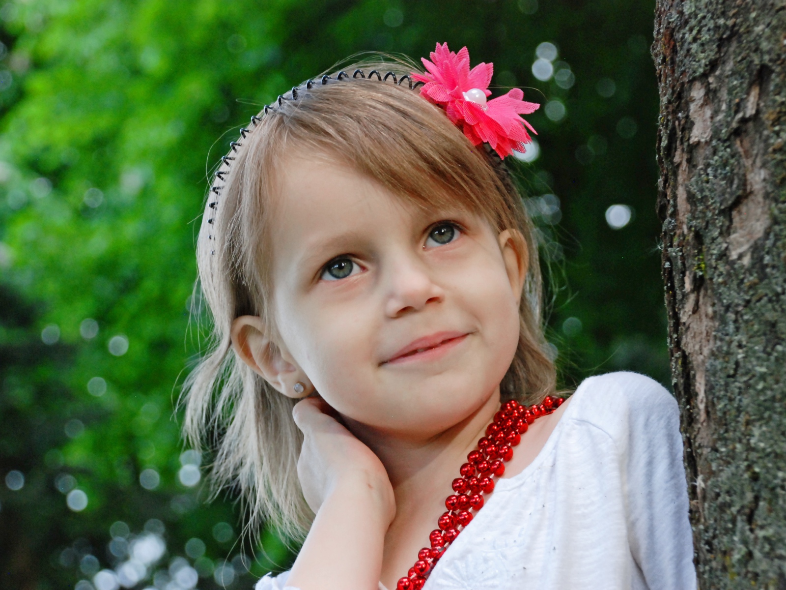 Маленькая улыбающаяся девочка у дерева 