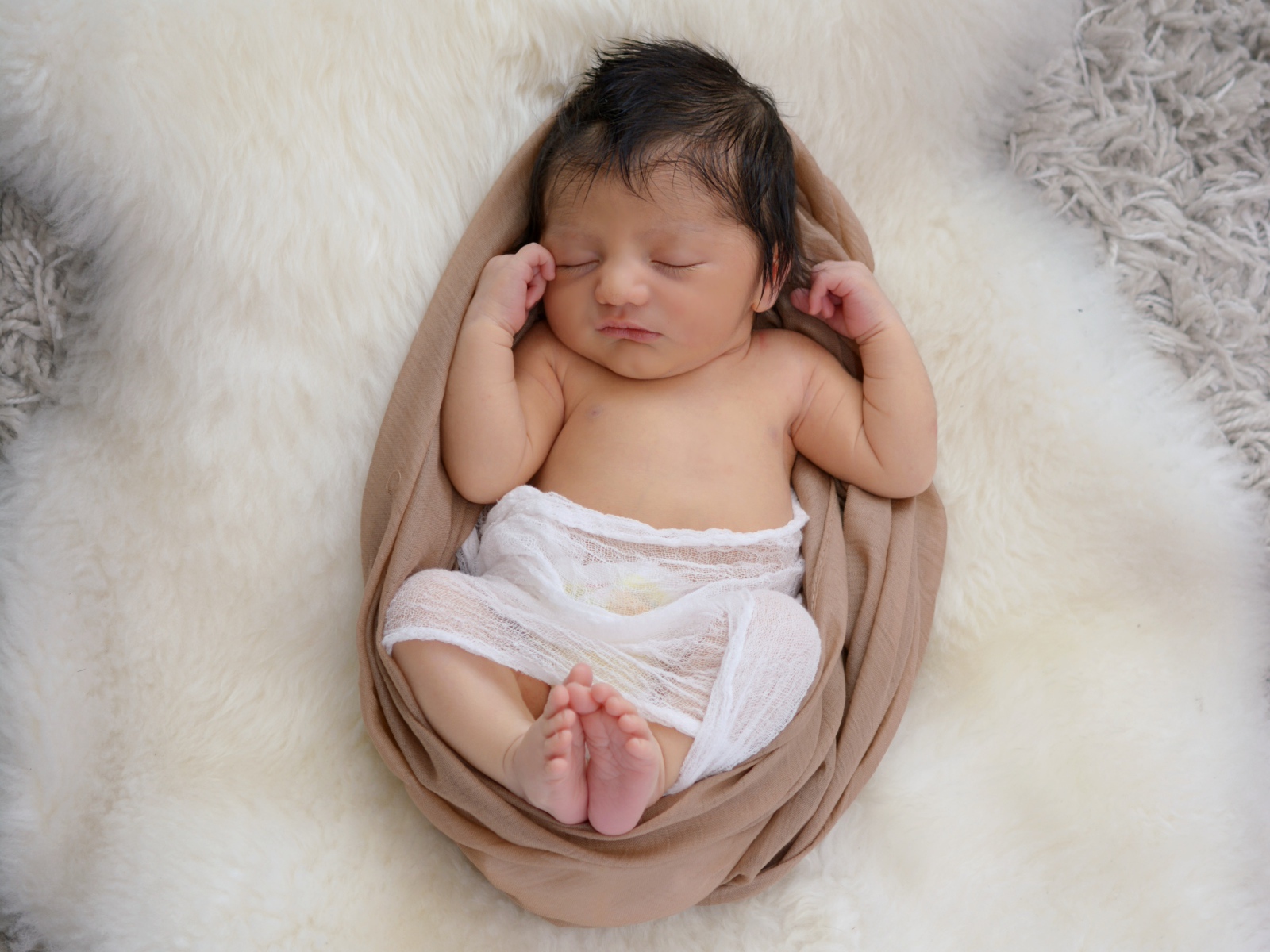 Спящий грудной ребенок на меховом покрывале 