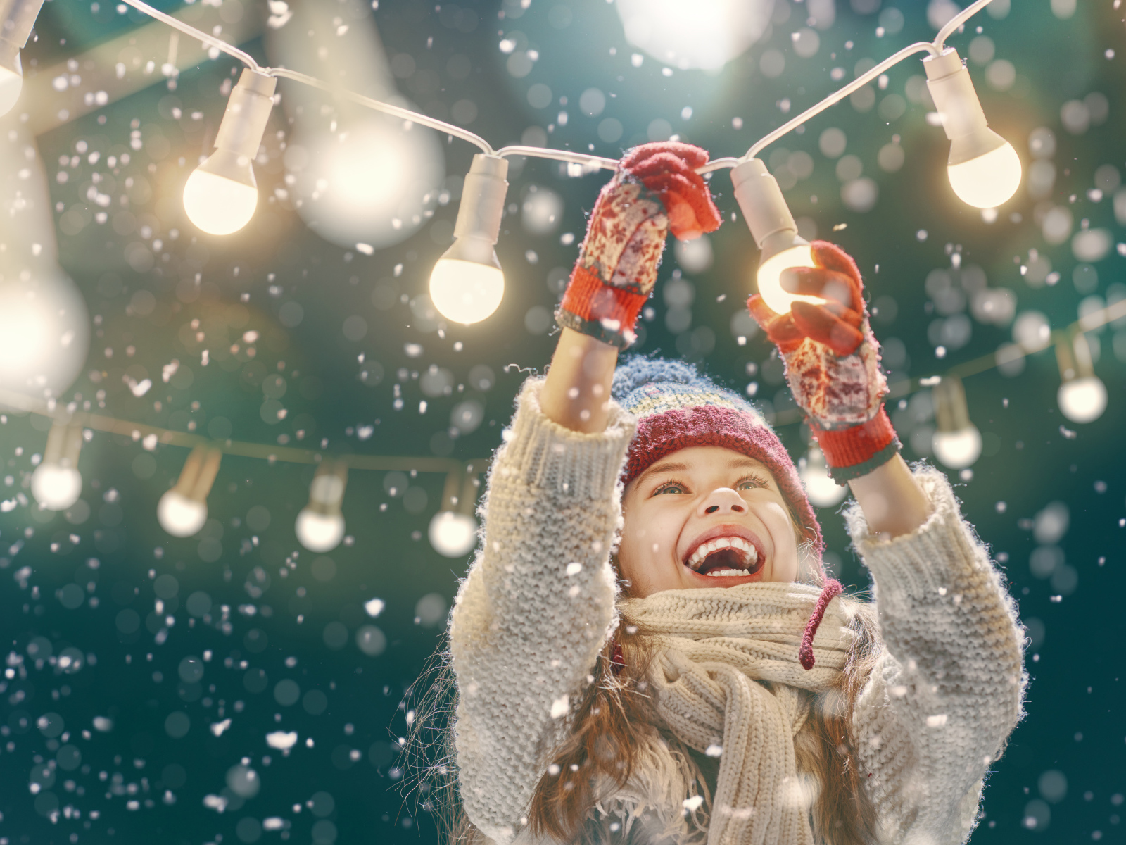 Улыбающаяся девочка вешает лампочки 