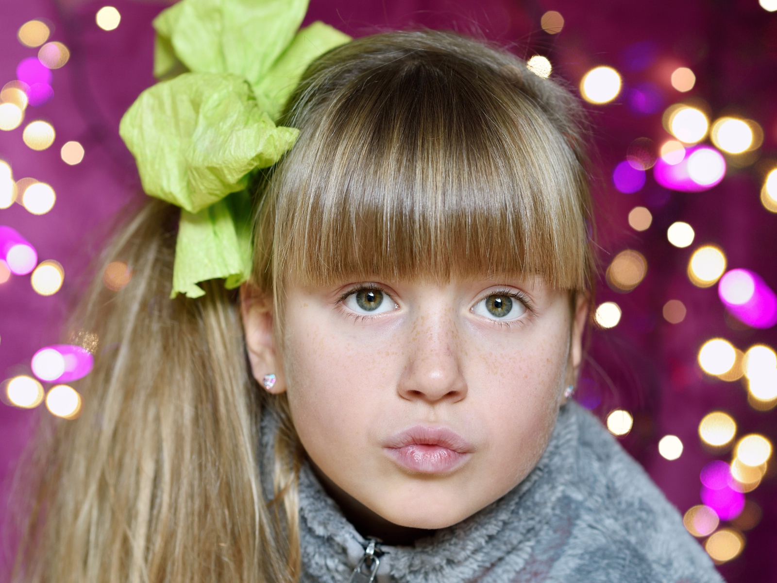 Лицо зеленоглазой девушки с бантом на голове 