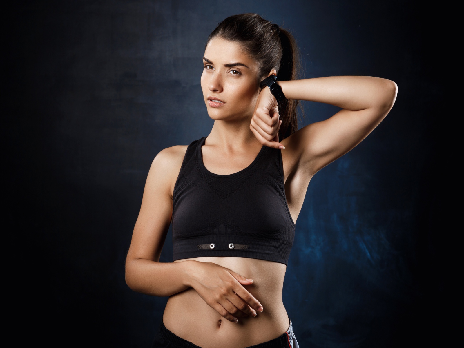 Спортивная девушка в черном топике с часами на руке 