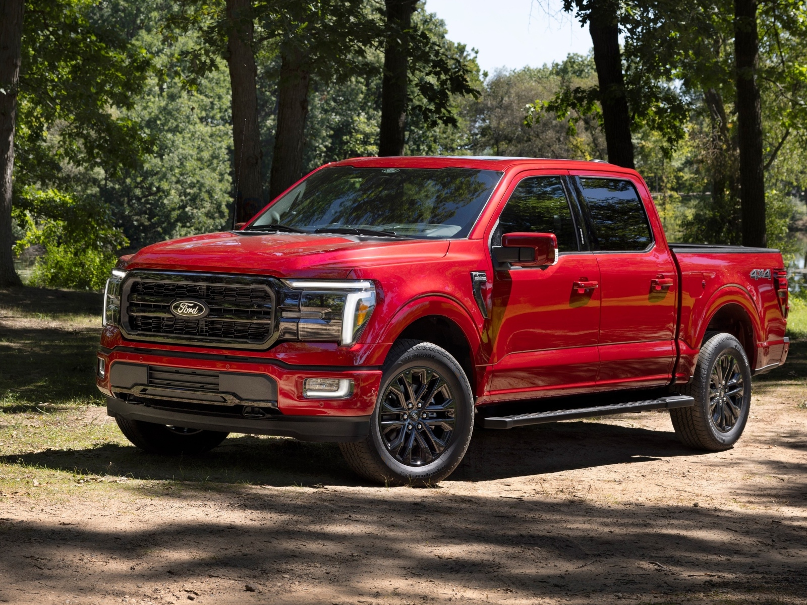 Большой красный Ford F-150 Lariat 2024 года в лесу