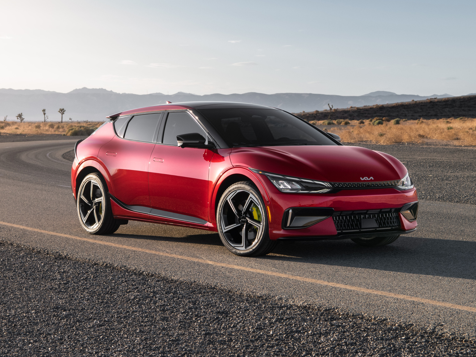 Красный автомобиль Kia EV6 GT 2023  года на дороге