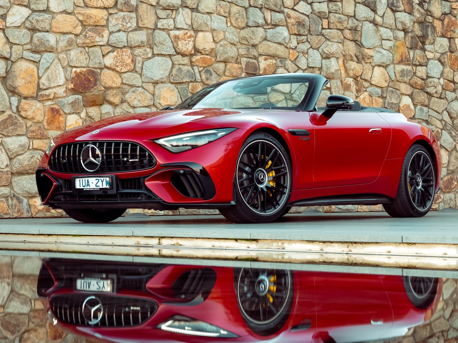 Красный Mercedes-AMG SL 63 4MATIC+ 2023 года на фоне стены