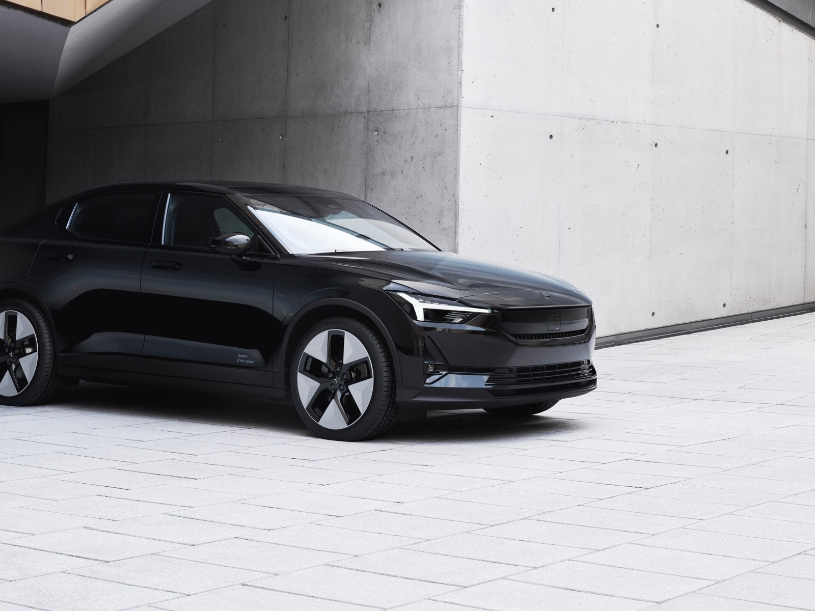 Черный автомобиль Polestar 2 2023 года у серой стены