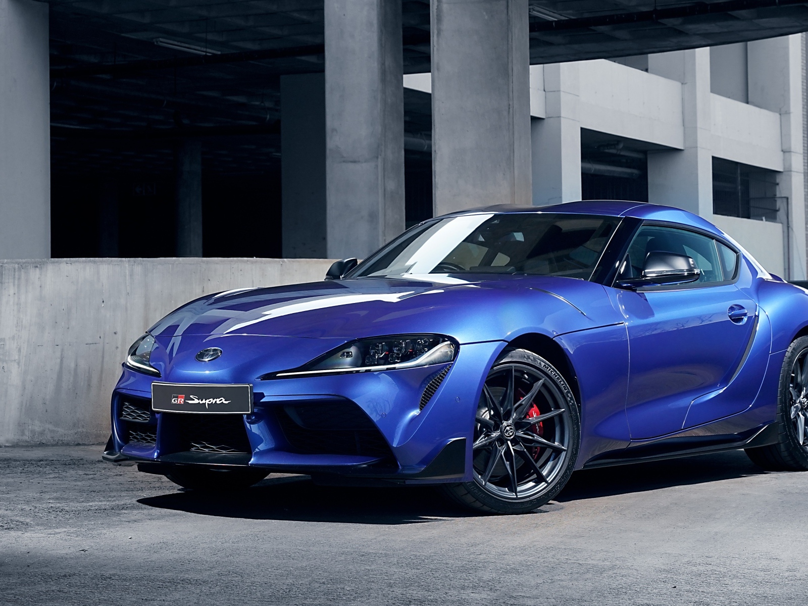 Синий автомобиль Toyota GR Supra 3.0 MT 2023 года у серого здания