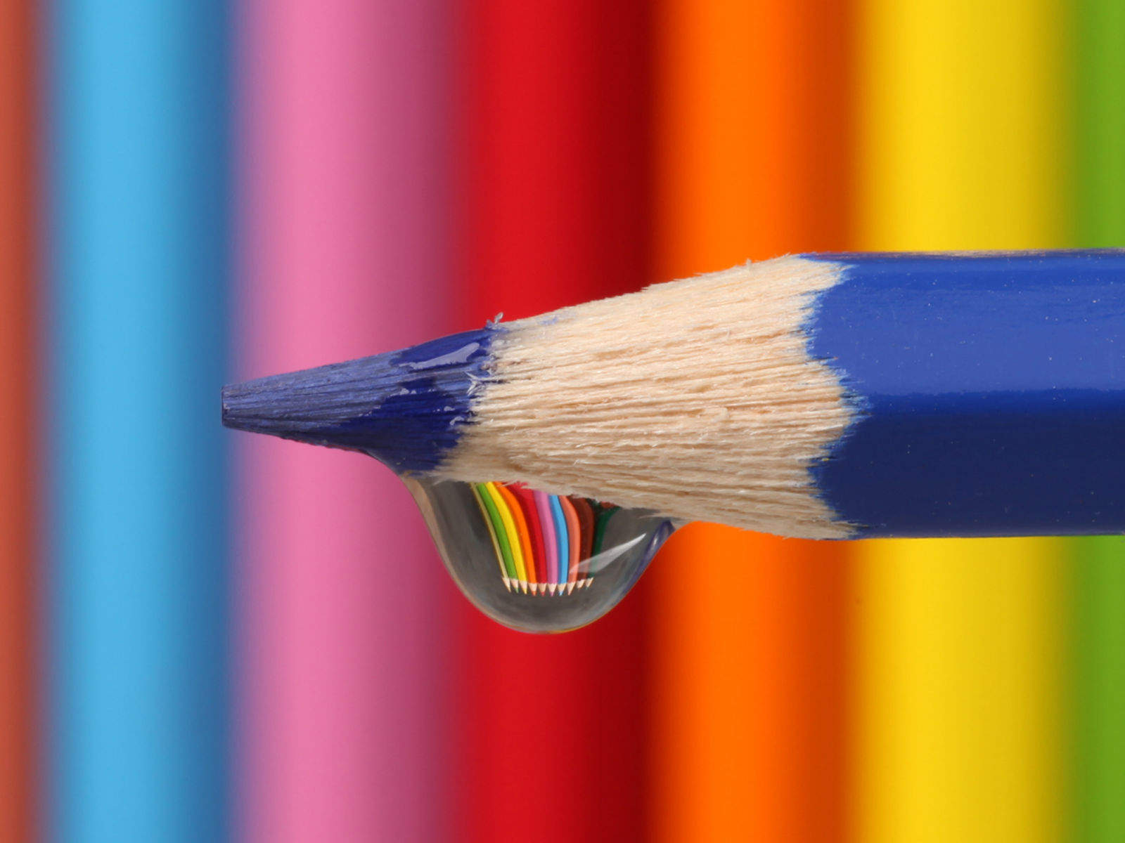 Капля воды стекает с синего карандаша