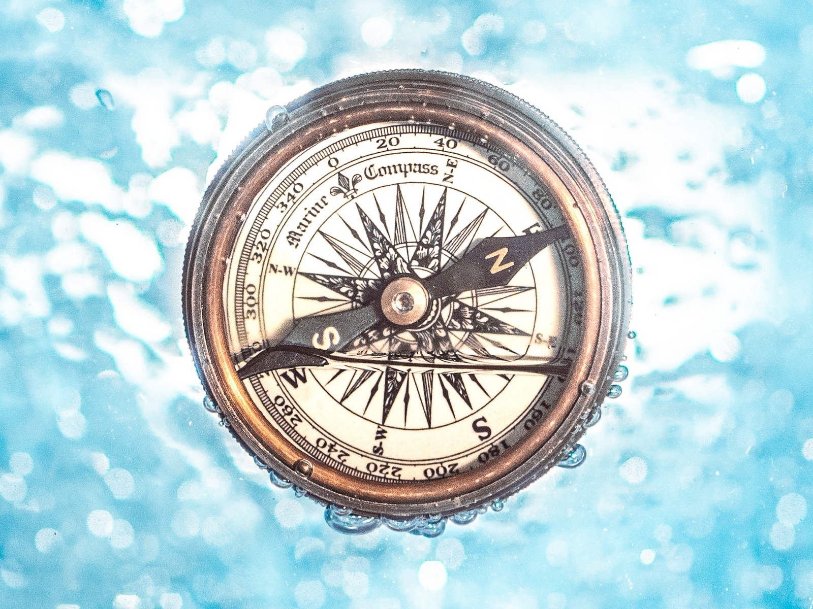 Старый компас в воде на голубом фоне
