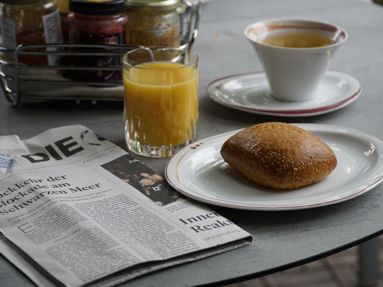 Булочка и стакан сока на столе с газетой