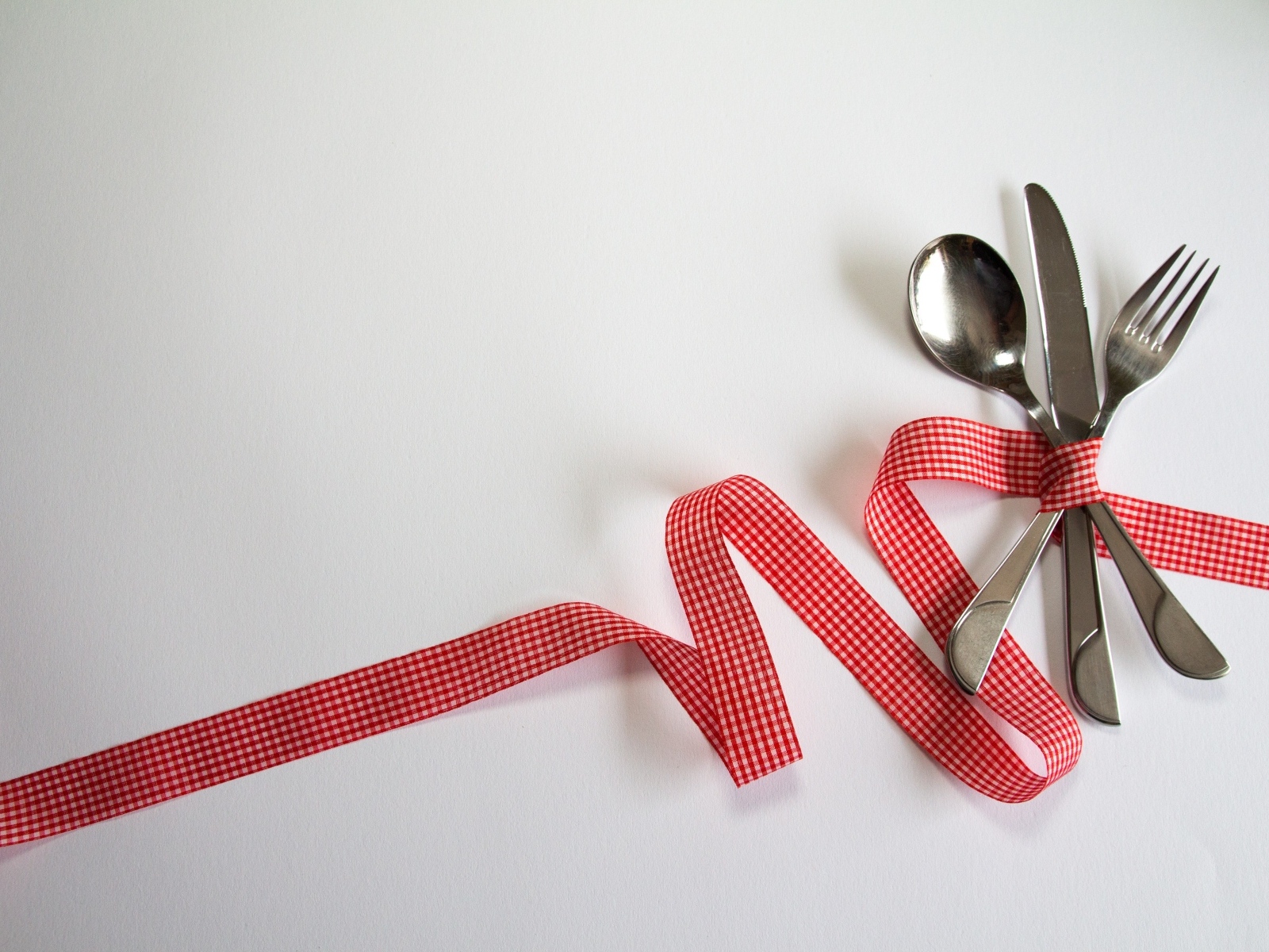 Столовые приборы перевязаны лентой на сером фоне