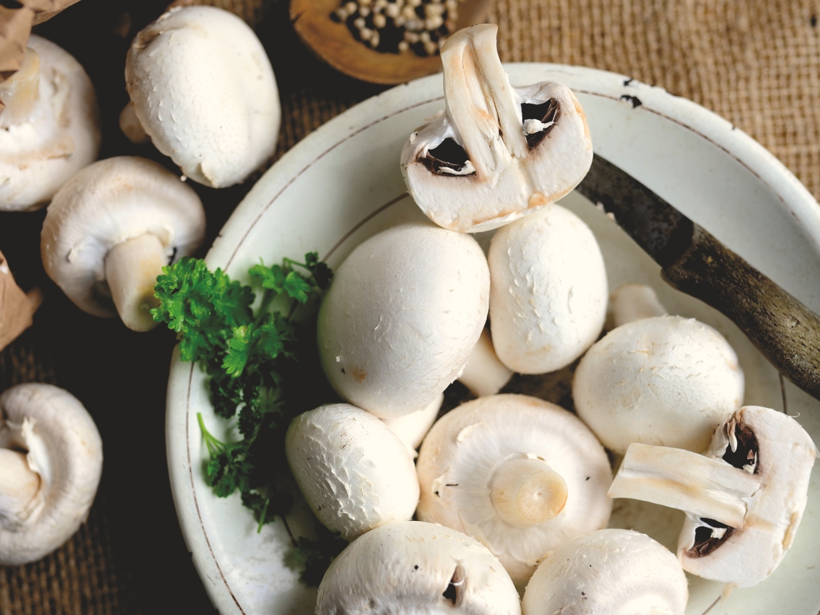 Свежие шампиньоны на тарелке на столе