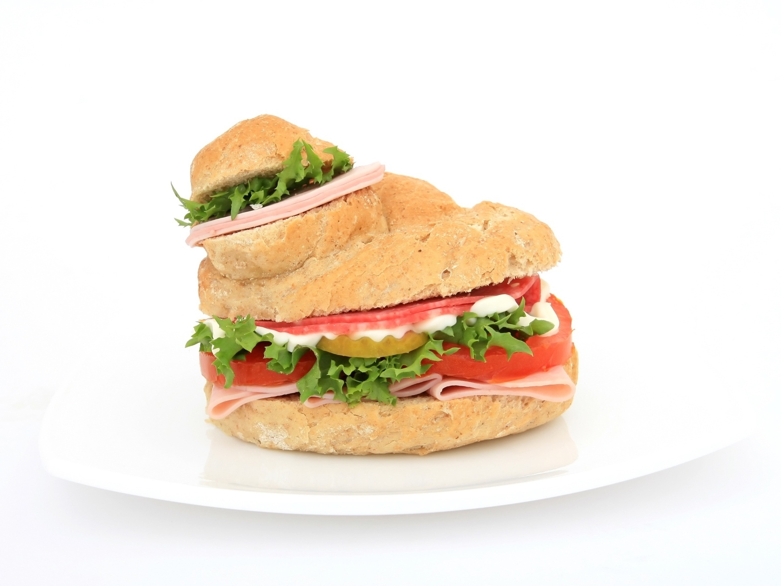 Гамбургер с колбасой, томатами и листьями салата на белом фоне