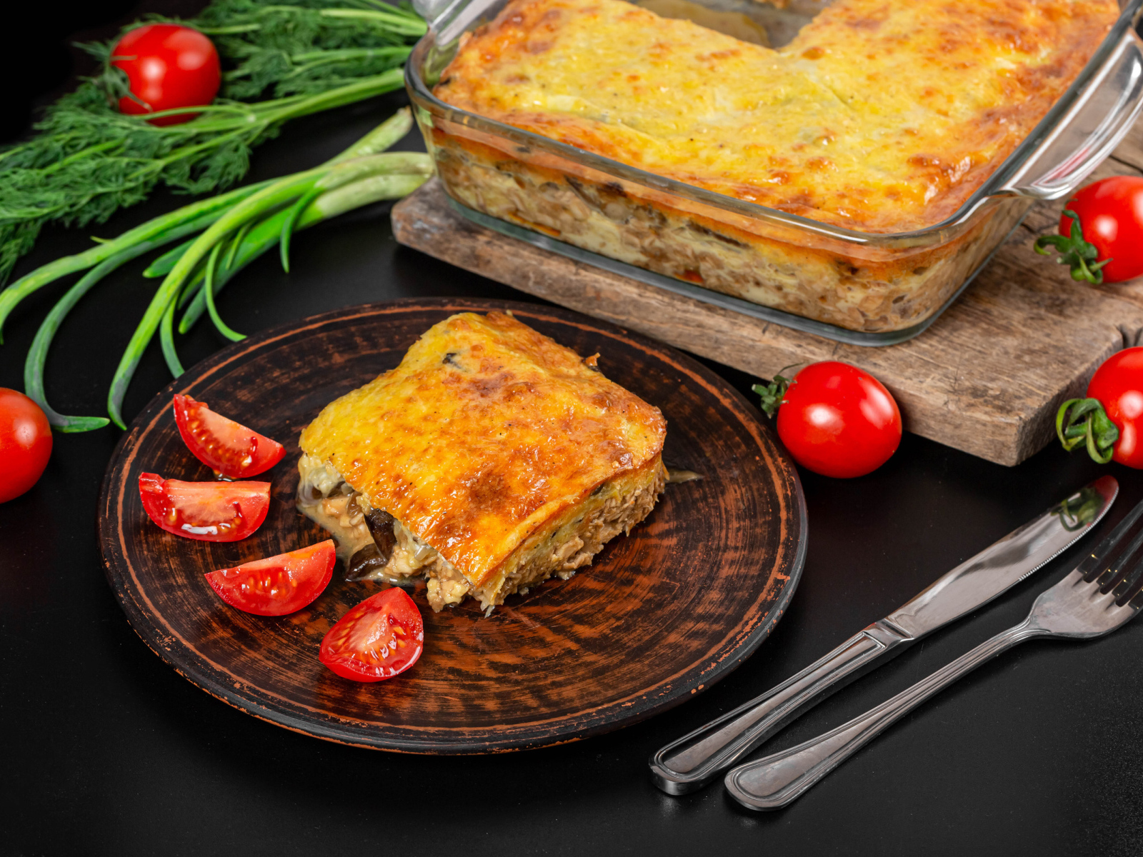 Лазанья на тарелке с помидорами и зеленью