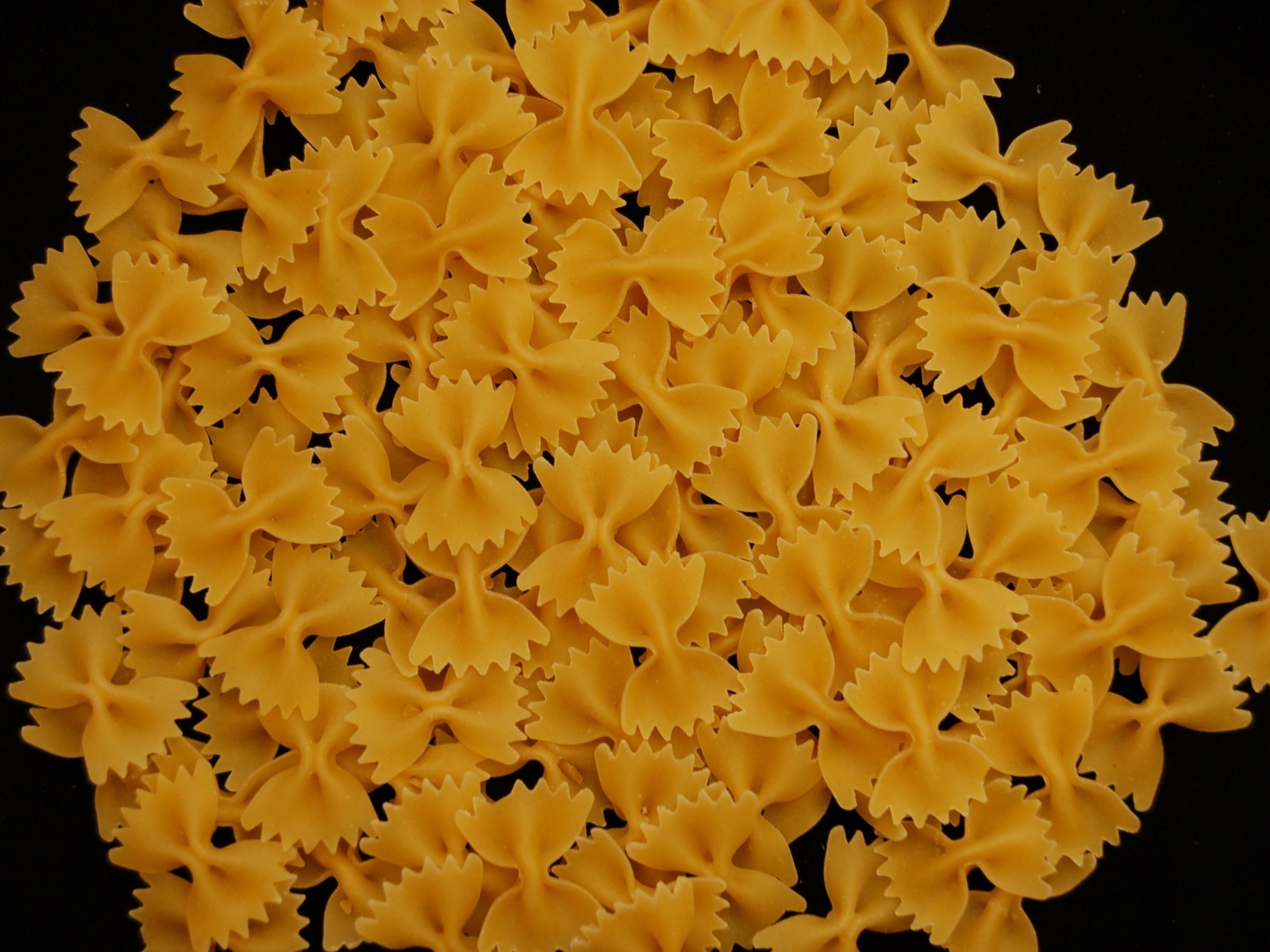 Макароны в форме бантиков на черном фоне