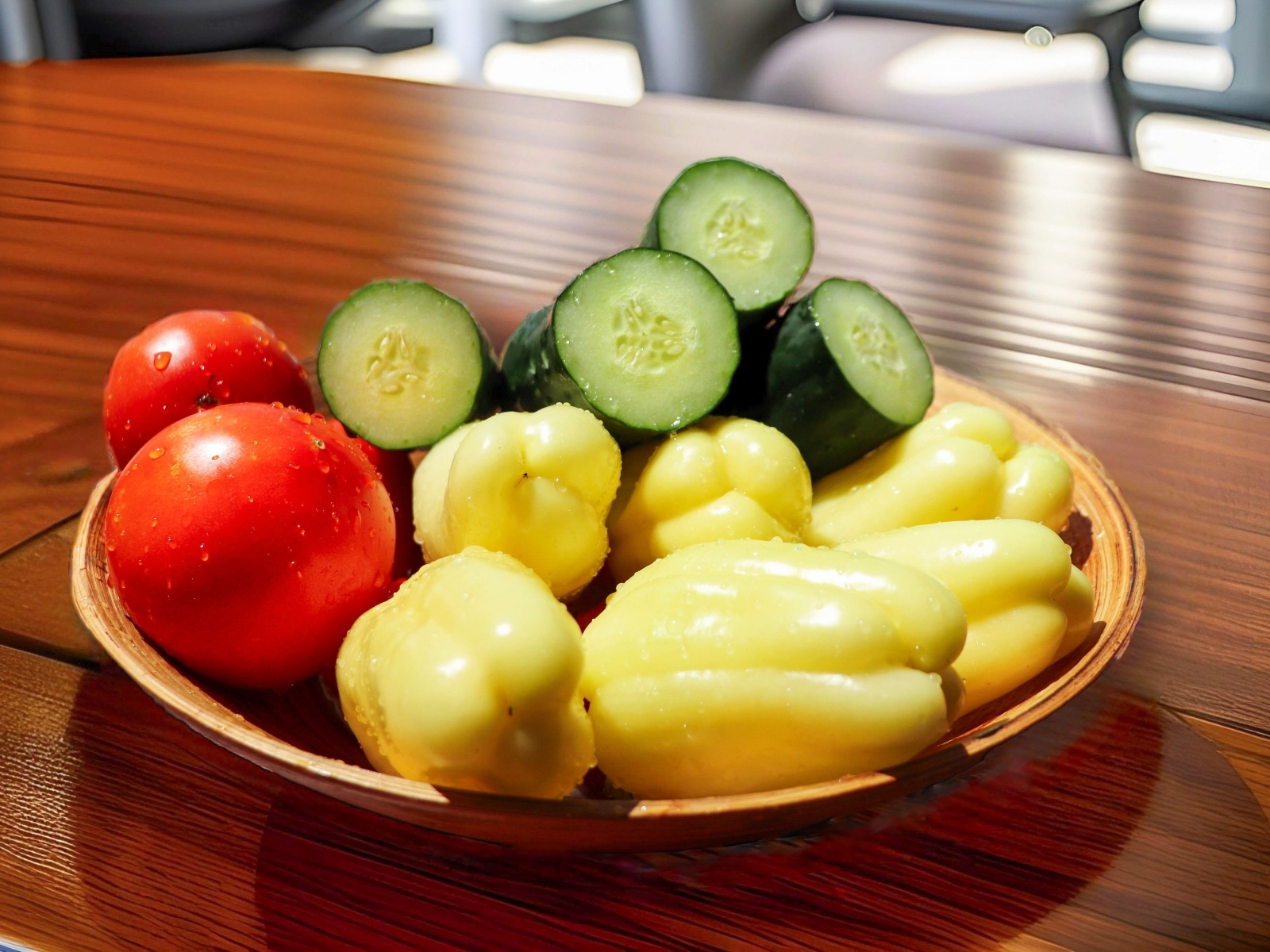 Перец, помидоры и зеленые огурцы на тарелке на столе