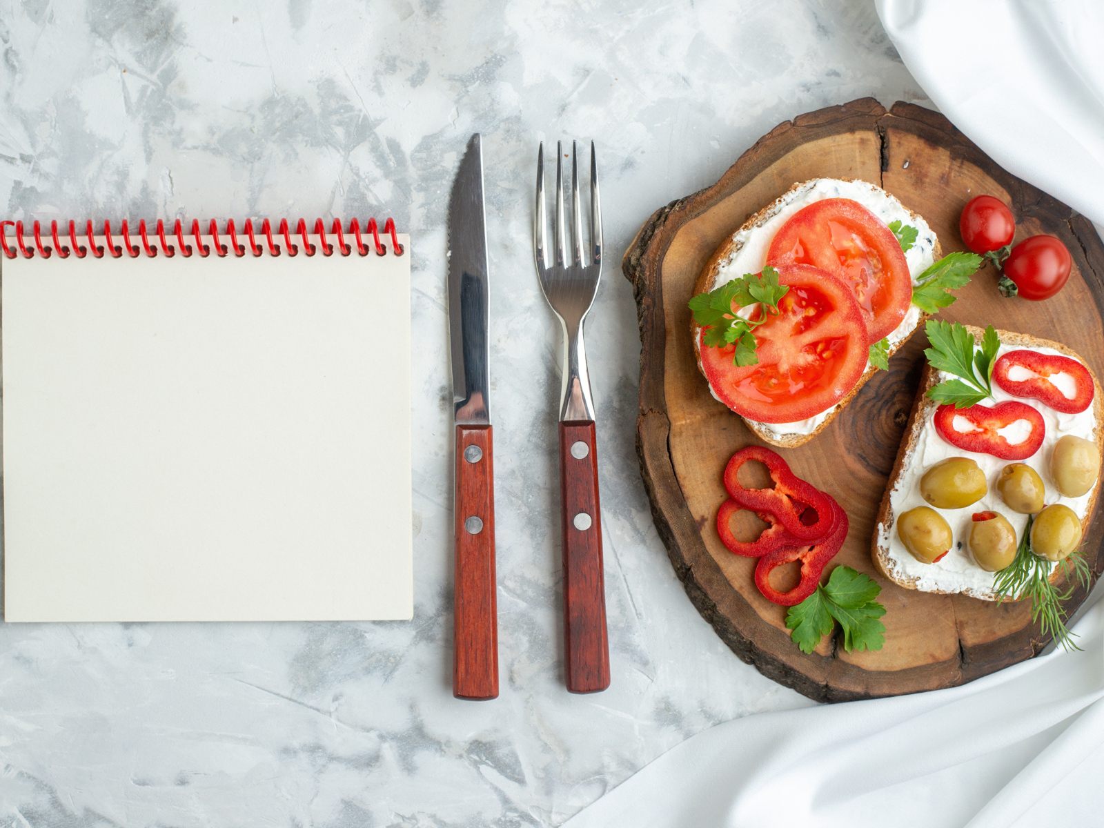 Бутерброды на столе со столовыми приборами и блокнотом