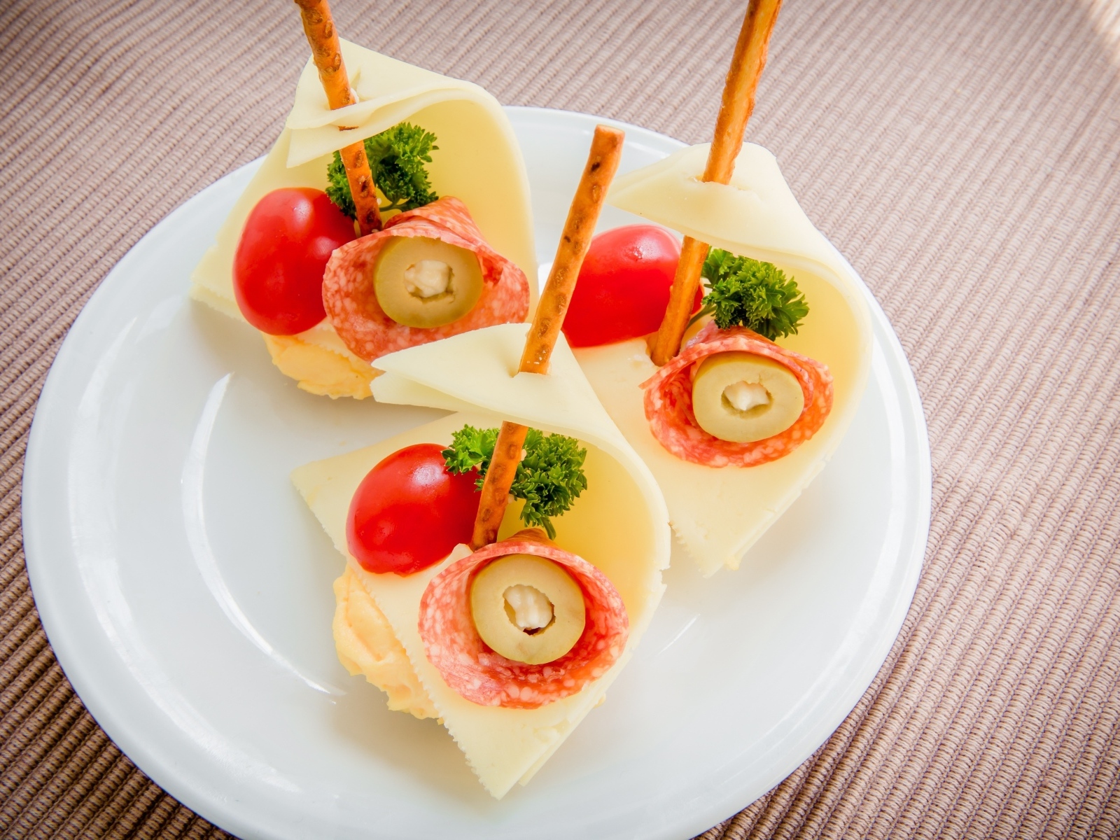 Бутерброды с колбасой, сыром и помидорами на белой тарелке