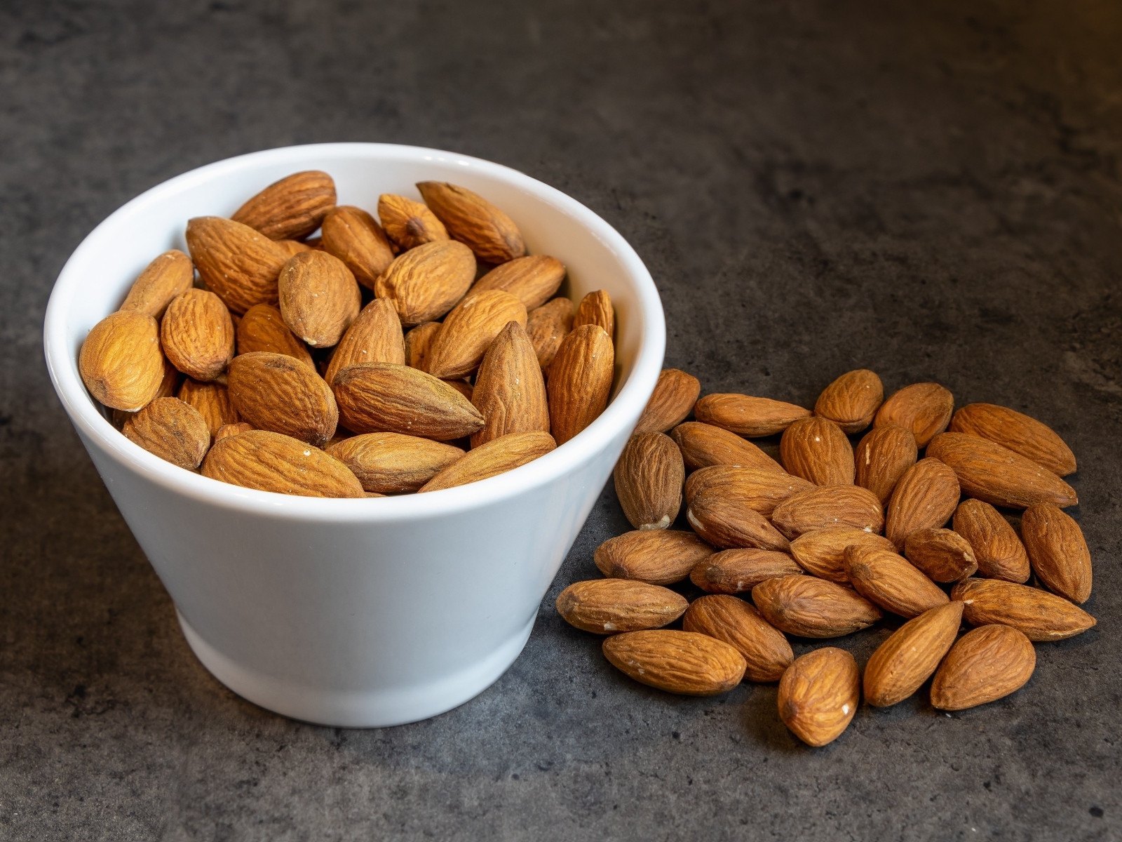 Миндальные орехи в белой пиале на столе