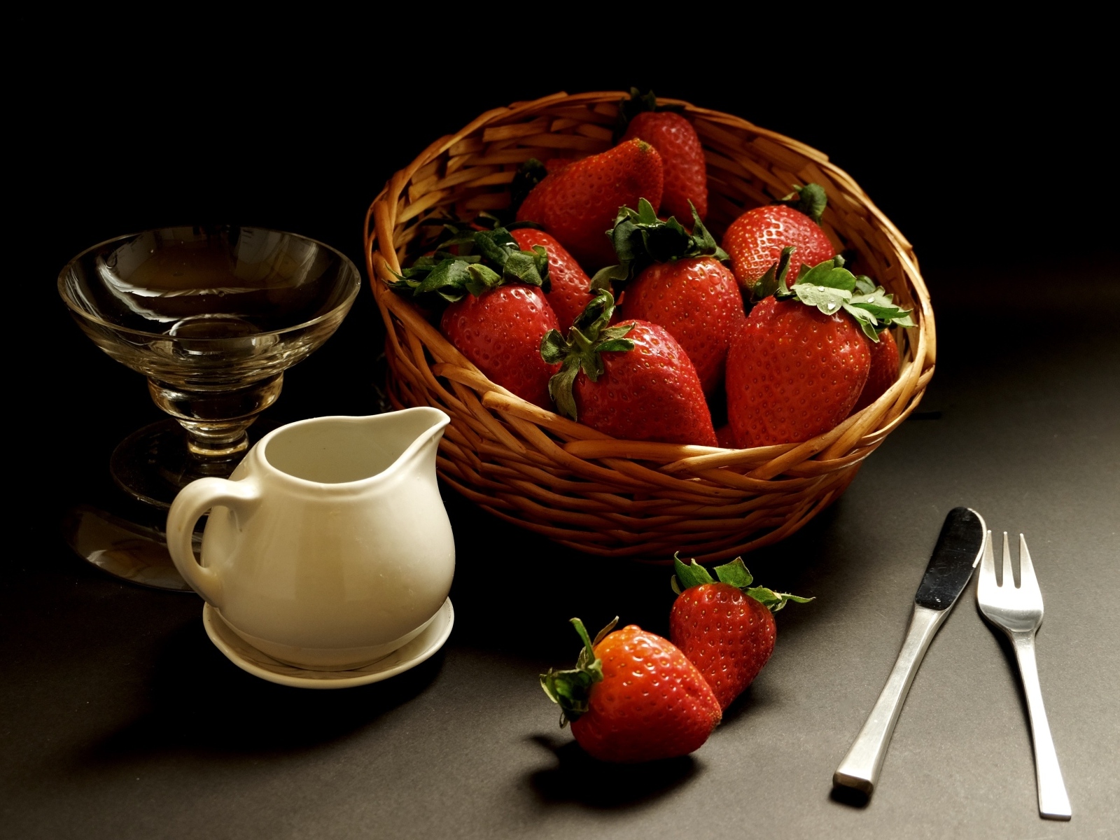 Корзина со спелой красной клубникой на столе с посудой