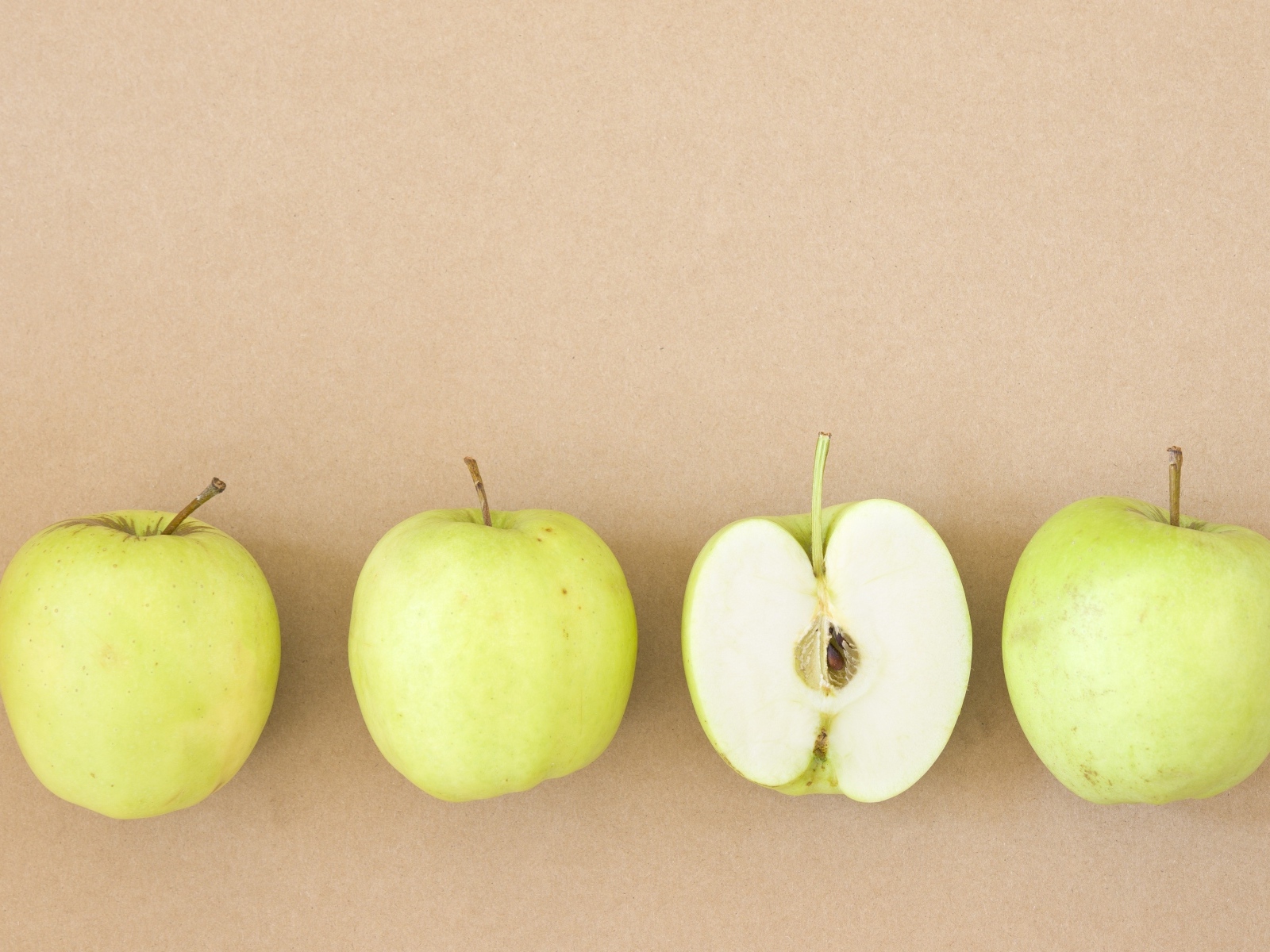 Четыре зеленых яблока на бежевом фоне 