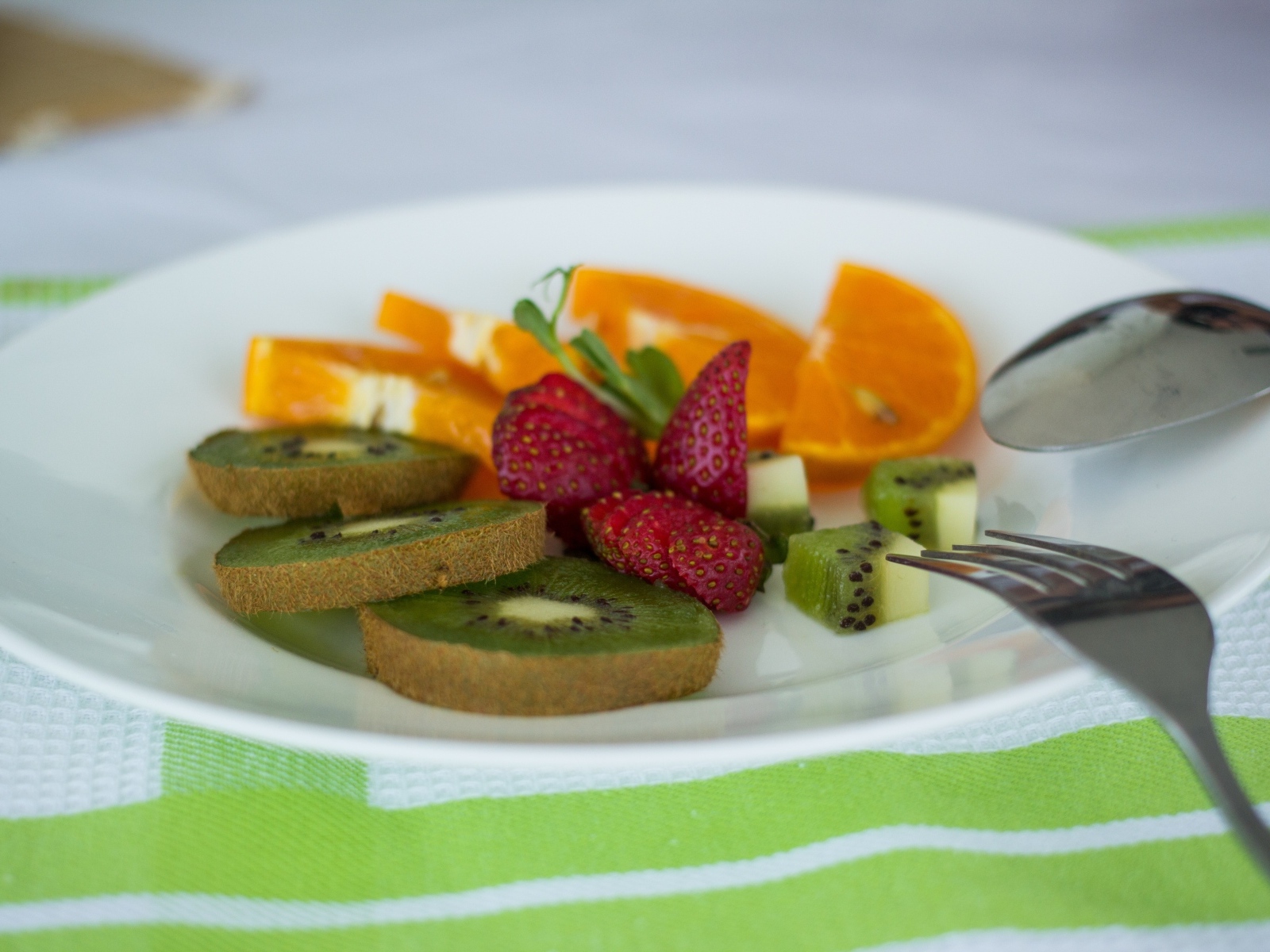 Свежие нарезанные фрукты на тарелке с вилкой