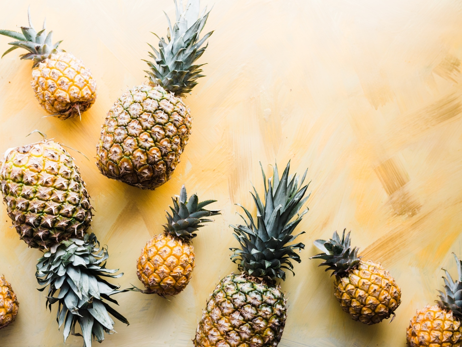 Много ананасов на желтом фоне
