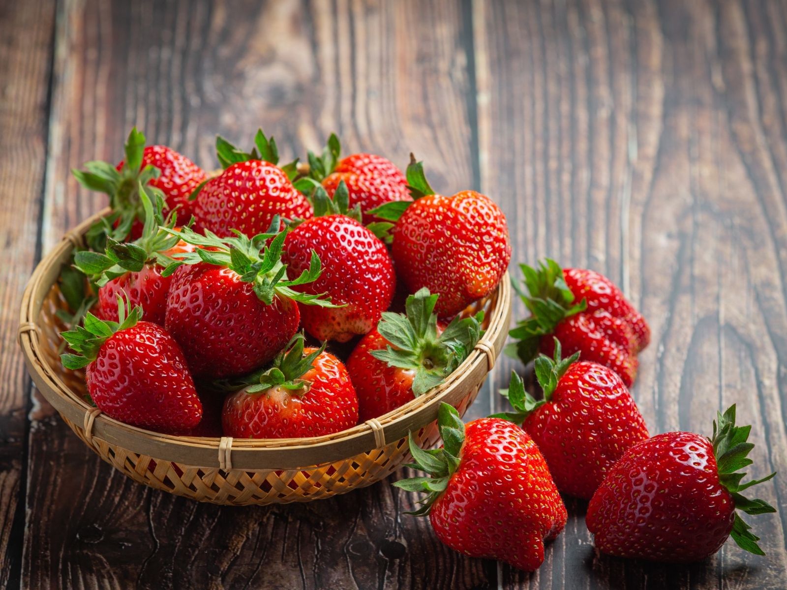 Много спелой красной клубники в деревянной посуде 