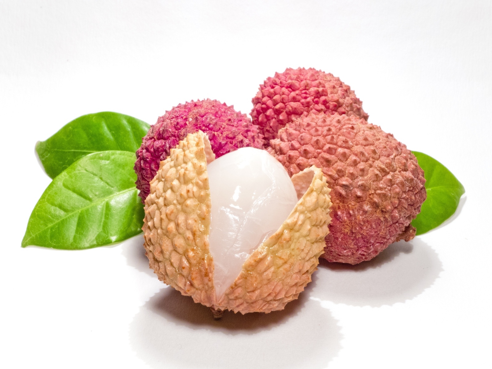 Спелые личи с зелеными листьями на белом фоне