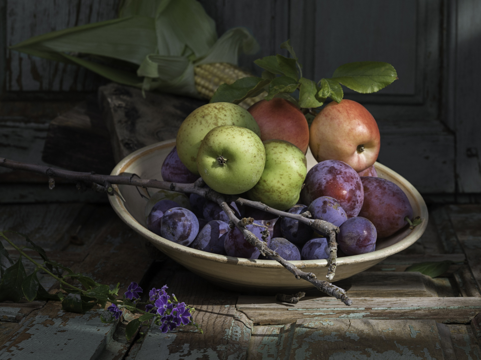 Спелые сливы на тарелке с яблоками