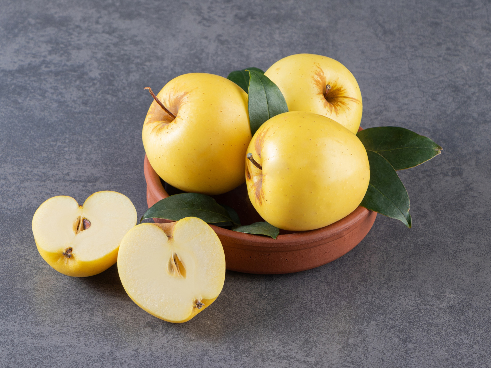 Желтые осенние яблоки на сером столе