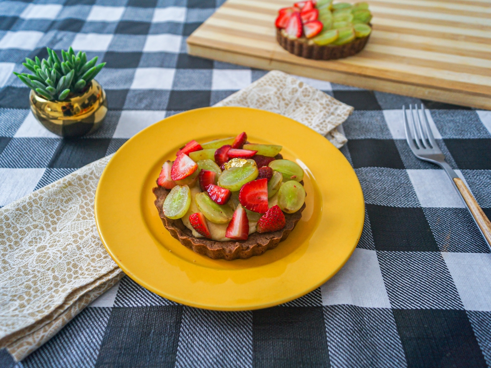 Пирожное с кремом и ягодами клубники и винограда